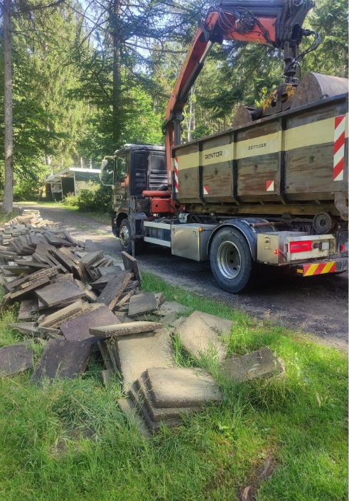 Lastbil med kran fjerner affald fra grund